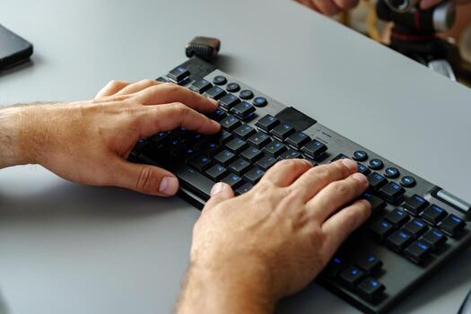 Hands typing on a modern keyboard in a workspace setting during daylight hours photo