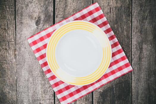 Empty plate on red and white checkered tablecloth in rustic setting photo
