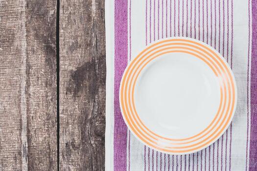 Empty plate rests on striped tablecloth in rustic setting ready for a meal photo