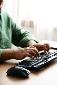 Person working on a keyboard while using a computer mouse in a well-lit room photo