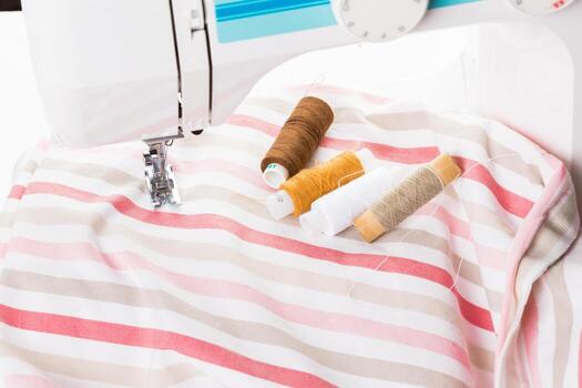 Sewing machine and colorful threads on fabric with striped pattern near it photo