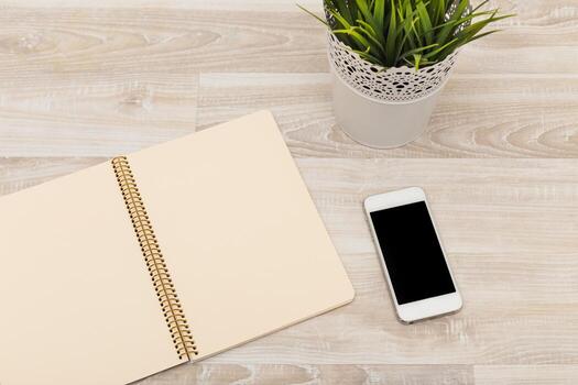 Simple workspace setup with blank notebook and smartphone on wooden table photo