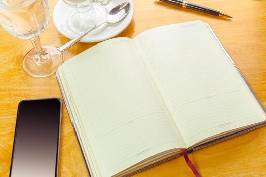 Notebook with blank pages and drinks on a wooden table in a cozy cafe setting photo