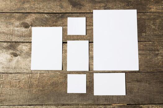 Different sizes of blank papers displayed on a rustic wooden surface photo