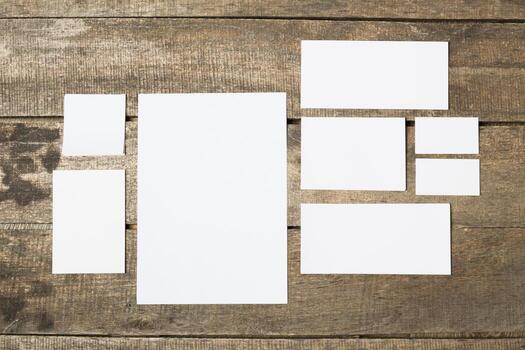 Blank sheets of paper arranged on a rustic wooden surface in various sizes photo
