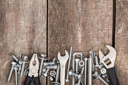 Collection of tools and hardware arranged on rustic wooden surface by a DIY enthusiast photo