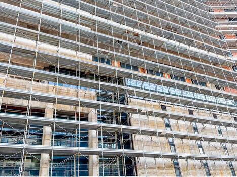 Facade of tall building covered in scaffolding. Symbol of engineering, progress and structural development in urban space. photo