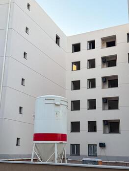 Courtyard of modern building with windows and cylindrical container. Architecture, construction, and urban residential development with exterior structural elements. photo
