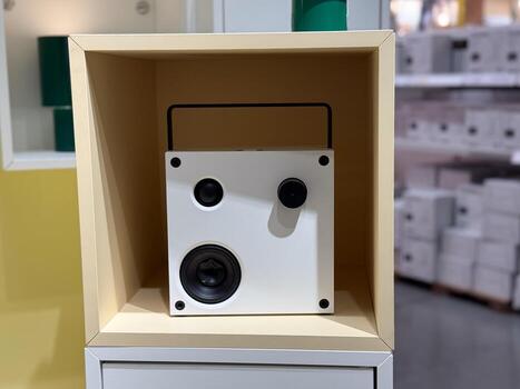 Square white speaker displayed on shelf inside retail showroom. Technology, product design and consumer electronics with minimal lifestyle and modern object presentation. photo