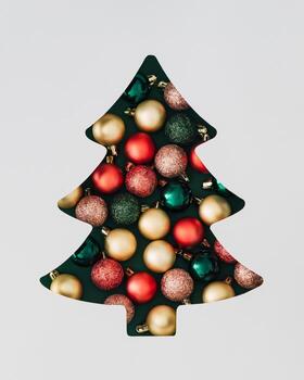 Winter composition with Xmas baubles visible through a Christmas tree shaped gap on green background. Minimal Christmas and New Year concept. Creative festive holiday layout. Flat lay, top view. photo