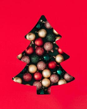 Winter scene with Xmas baubles visible through a Christmas tree shaped gap on green background. Minimal Christmas and New Year concept. Creative festive holiday layout. Flat lay, top view. photo