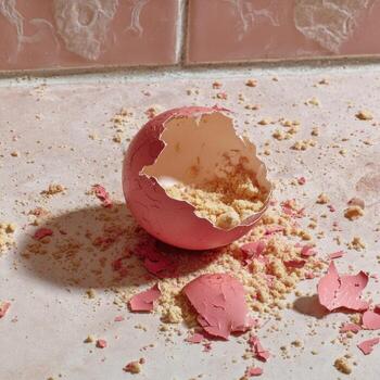 A pink egg is broken on a white counter photo