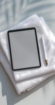 Tablet and pen on towel with palm tree photo