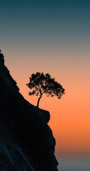 un solitario árbol soportes en parte superior de un acantilado a puesta de sol foto