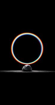 A black rock with a rainbow ring around it photo