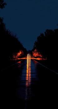 A wet road at night with a light shining on it photo