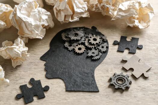 A silhouette of a human head with gears and crumpled paper photo