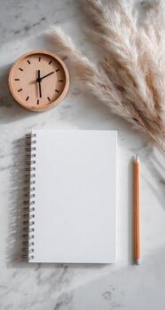 Blank notebook, pen, clock and pampas on marble table photo