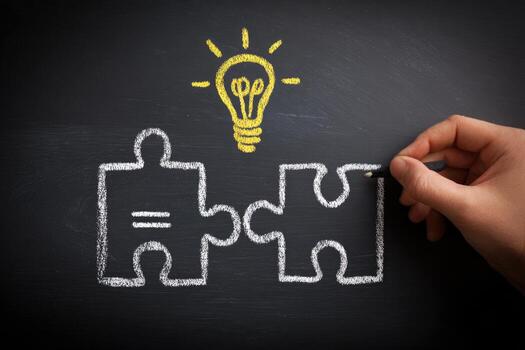 Hand drawing puzzle pieces on blackboard with light bulb photo