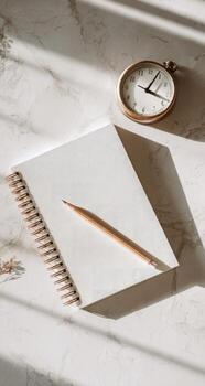 Blank notebook, pen, clock and a notepad on a marble surface photo