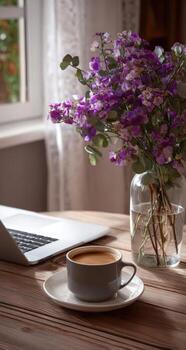 A laptop and a vase of flowers on a table photo
