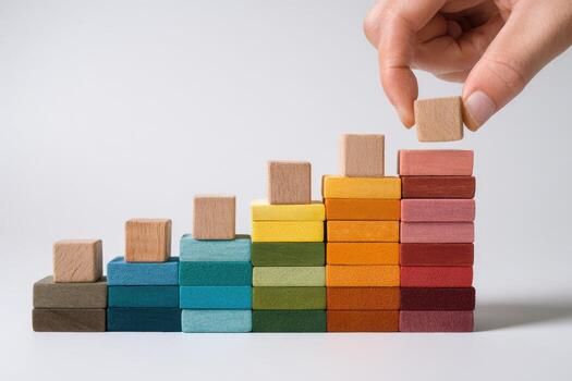 A person is placing wooden blocks on a colorful stack photo