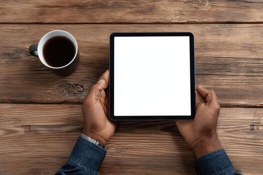 Hands holding tablet pc with blank screen on wooden table photo