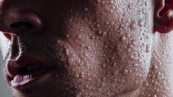 närbild sekvens av en mannens ansikte med blänkande droppar av vatten, visa upp de intensitet och känsla av de ögonblick, highlighting de samspel av ljus och textur video