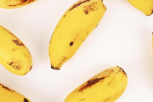 Multiple yellow bananas fill the frame creating full, tight pattern with white space separation. photo