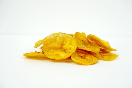 Low-angle view of stacked banana chips isolated on white background with clean composition for snack branding visuals. Food concept photo