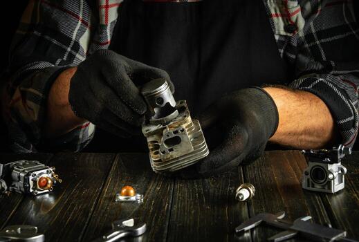 Repair of a chainsaw engine after a breakdown by the hands of a master on a table in a workshop. photo