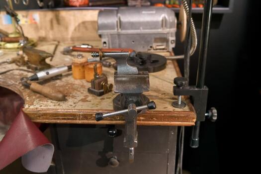 Workbench with various tools and a clamp at a craft workshop in the late afternoon photo