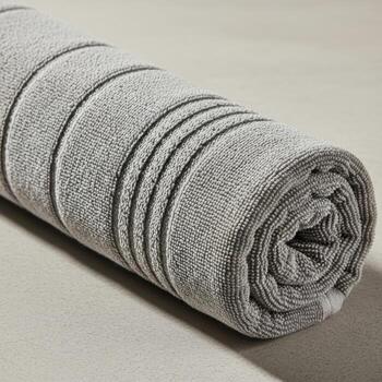 Rolled up textured towel with subtle stripes in muted green and grey tones isolated on white background photo