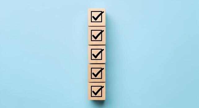 Wooden blocks with check marks aligned vertically on a light blue background symbolizing a checklist, completion, and success photo