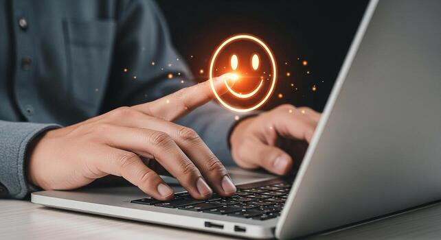 Person using laptop computer interacting with a glowing smiley emoticon signifying positive feedback satisfaction and excellent user experience in a digital workspace photo