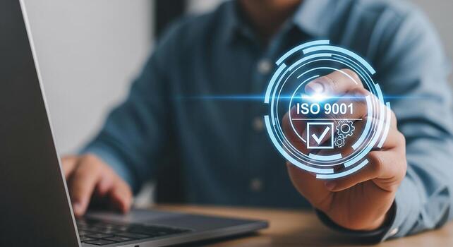 Businessperson working on laptop computer in modern office actively selecting ISO 9001 quality management system certification on a digital interface signifying commitment to excellence and business s photo