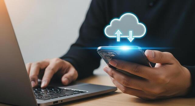 Person using smartphone and laptop to upload and download data to the cloud, working from home office, concept of remote work, digital nomad, and efficient technology photo