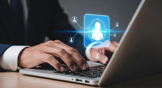 Businessman using laptop computer to manage digital profiles and network connections in a modern office setting, showcasing online collaboration and communication photo