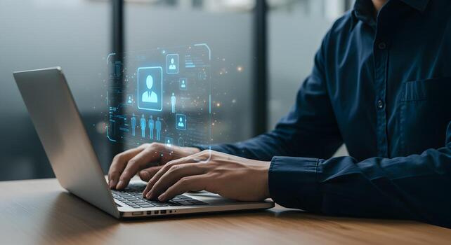 Man using laptop computer to manage digital profiles and data working in a modern office with a futuristic user interface showing a concept of human resources networking and digital identity photo