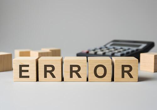 Wooden cubes spelling ERROR on a table near a calculator depicting a mistake fault or an error in calculation or system conveying a sense of problem troubleshooting and technical issue photo