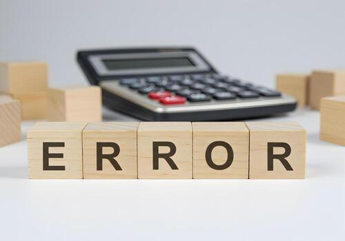 Wooden blocks spelling ERROR on white surface with calculator in background concept of accounting mistake financial problem calculation error data analysis and problemsolving photo