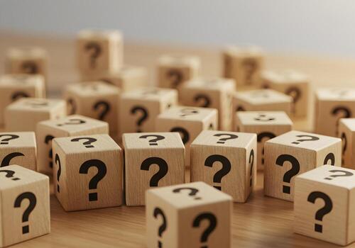 Wooden cubes with question marks scattered on a table representing uncertainty doubt questions and the search for answers photo