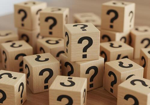 Wooden blocks with question marks stacked on a table representing uncertainty doubt questions and the search for answers The image evokes a sense of mystery and curiosity perfect for concepts related photo