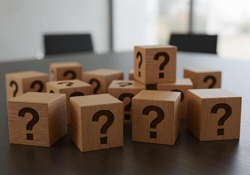 Wooden cubes with question marks on a table in a modern office symbolizing uncertainty and the search for answers photo