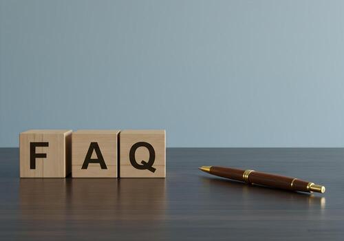 FAQ spelled out on wooden blocks on a dark desk next to a pen suggesting answers questions and solutions for business or customer service photo