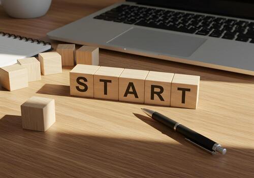 Wooden blocks spelling START on a desk with laptop and pen signifying a new beginning and motivation for success in business and life The warm lighting and office setting create a mood of optimism and photo