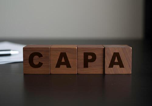 Wooden blocks spelling out CAPA on a dark desk signifying Corrective Action Preventive Action in business and quality management The concept evokes themes of process improvement and risk mitigation id photo