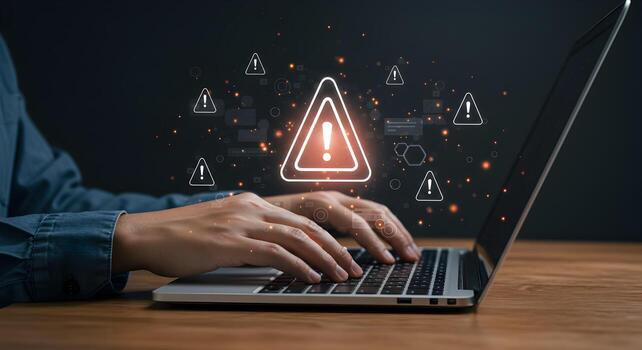 Person working on laptop computer with warning signs and alerts appearing on screen indicating a system error or security breach The image conveys a sense of urgency and concern related to cybersecuri photo