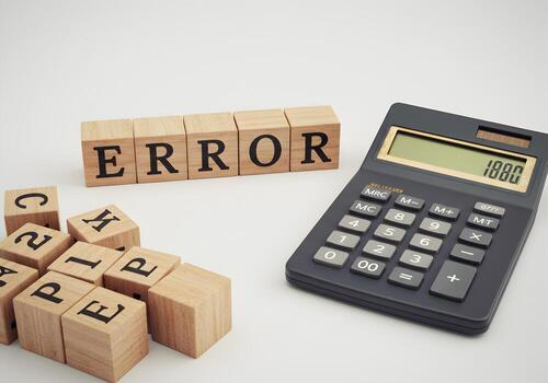 Wooden Blocks Spelling Error Next to Calculator Showing Math Calculation Mistake Representing an Accounting or Financial Error Concept photo