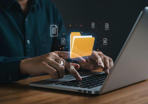 Person managing digital files and folders using a laptop computer at a desk showcasing efficient data organization and digital workflow photo